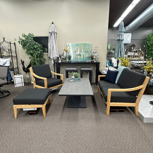 A modern 3-piece living room furniture set featuring a two-seat sofa, a matching armchair, and a square ottoman, arranged around a small rectangular coffee table on a textured gray carpet in a showroom.