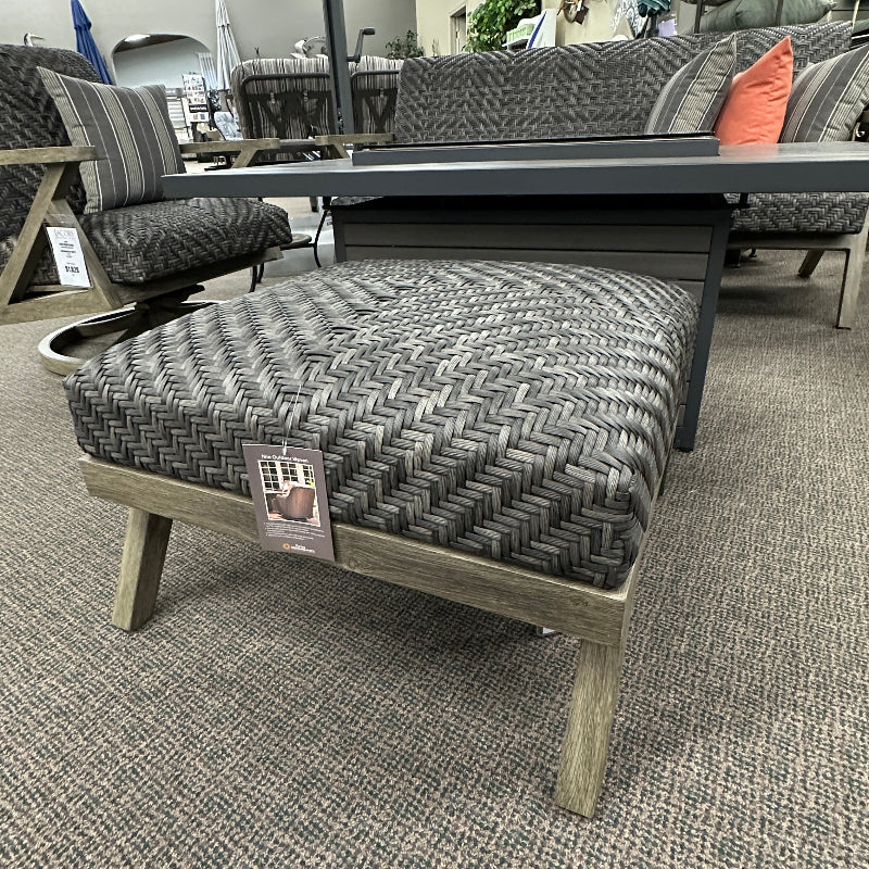 Gray patterned ottoman with a price tag in an indoor setting