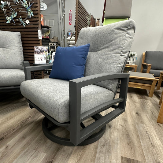 Gray swivel chair with a blue pillow in a furniture store setting