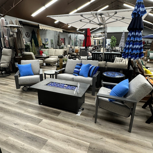 Outdoor furniture set with chairs, tables, and a fire pit in a showroom.