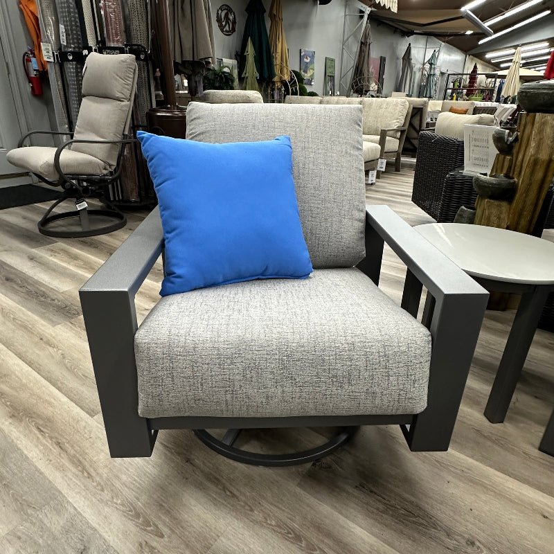 Gray swivel chair with a blue pillow in an indoor setting with various furniture and decor items.