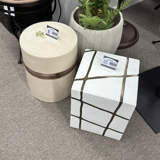Decorative stools with geometric patterns and a potted plant on a gray floor.