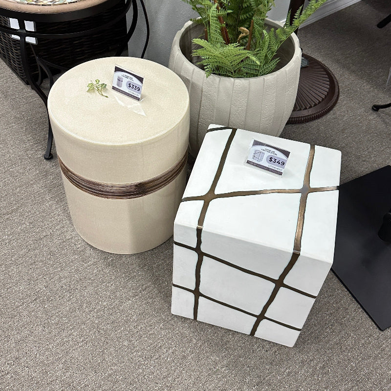 Decorative stools with geometric patterns and a potted plant on a gray floor.