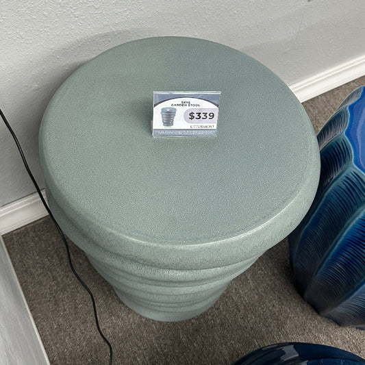 Green decorative pot with a price tag on a gray floor.