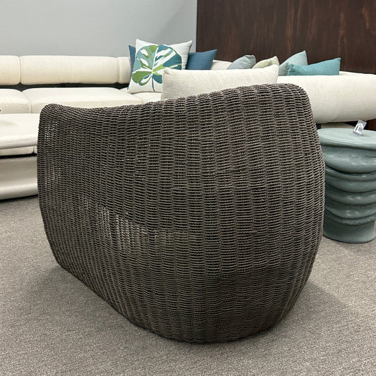 Wicker side table in a furniture store with sofas and decor in the background