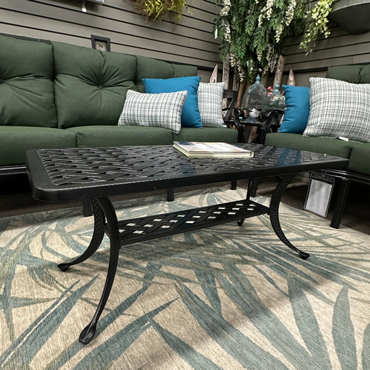 Outdoor patio with green cushioned sofa, black metal table, and decorative elements on a wooden deck.