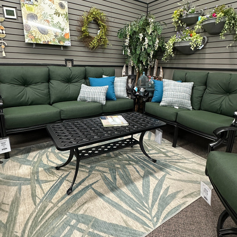 Outdoor patio area with green sectional sofa, coffee table, and decorative plants.