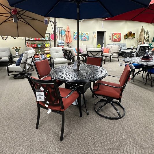 Outdoor furniture set with table and chairs under a large umbrella in a showroom.