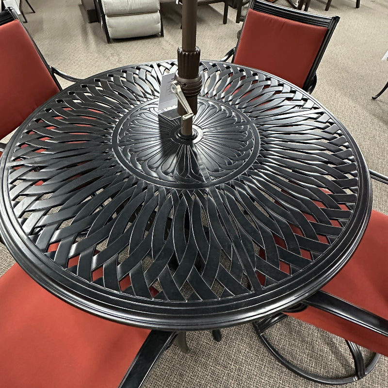 Black metal patio table with umbrella stand in an indoor setting