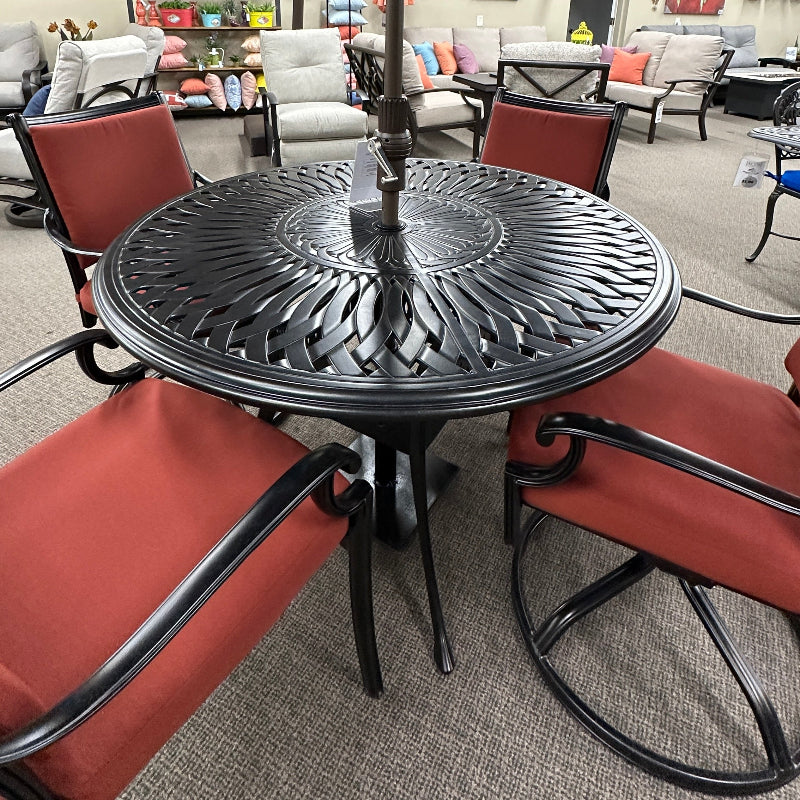 Outdoor patio set with table, chairs, and umbrella in a showroom setting.