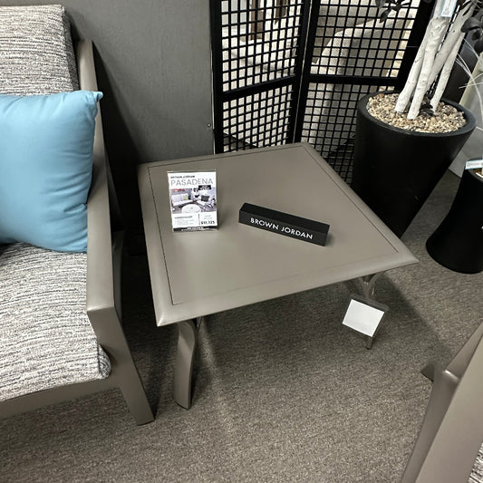 Gray chair with a blue pillow, small table, and decorative items in an indoor setting.