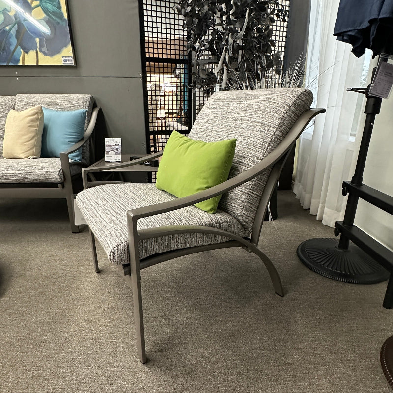Living room with gray carpet, gray armchair with a green pillow, and a painting on the wall.