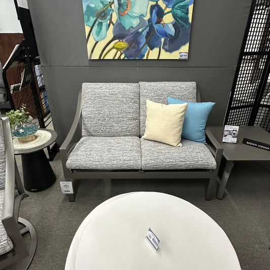 Gray sofa with colorful cushions against a gray wall with a floral painting.
