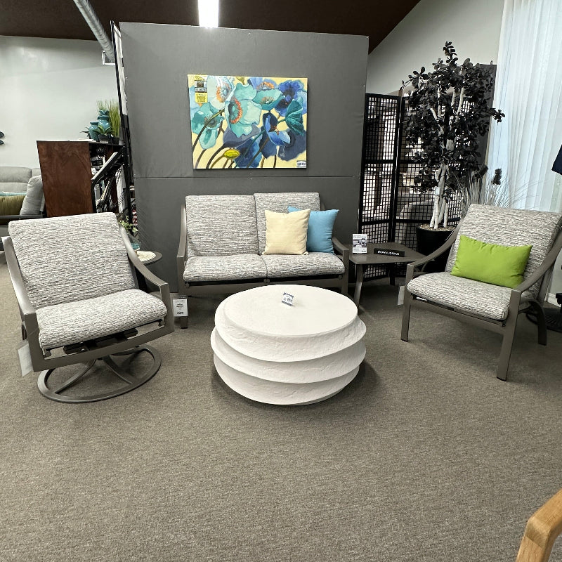 Modern living room setup with gray sofa, armchairs, and a white ottoman.
