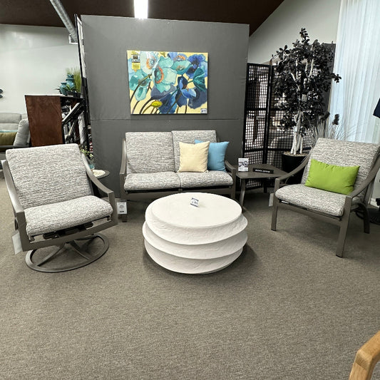 Modern living room setup with gray sofa, armchairs, and a white ottoman.