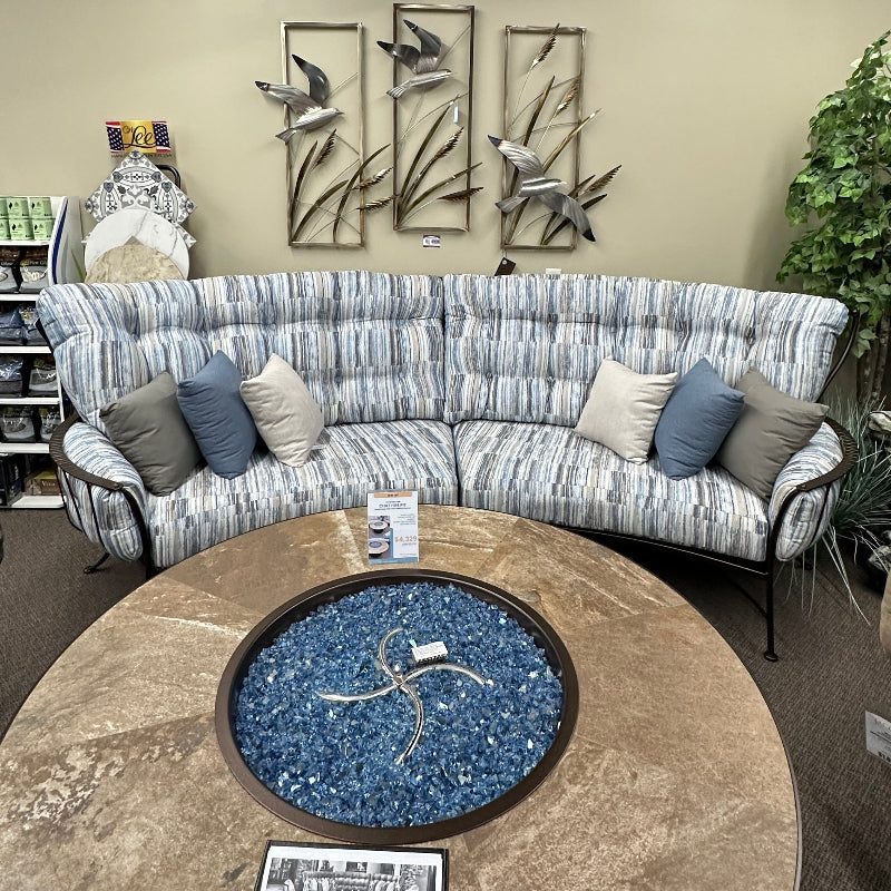 Sectional sofa with decorative pillows in a room with a round stone table and wall art.