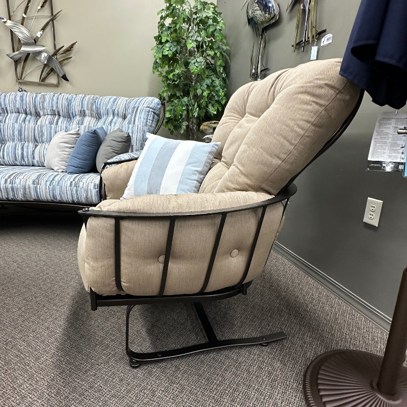 Beige recliner chair in a room with a couch and decorative items on the wall.