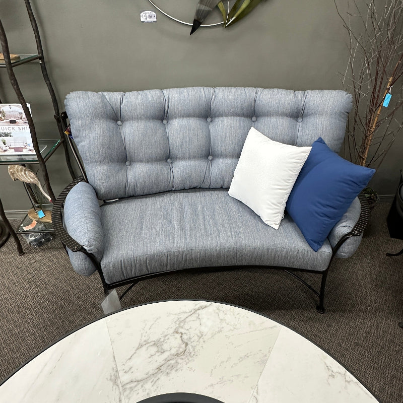 Gray tufted sofa with decorative pillows in a room setting.