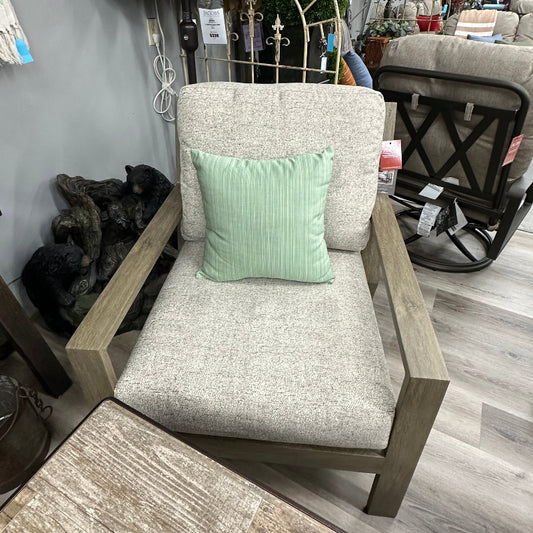 Chair with a green pillow in an indoor setting with various items in the background