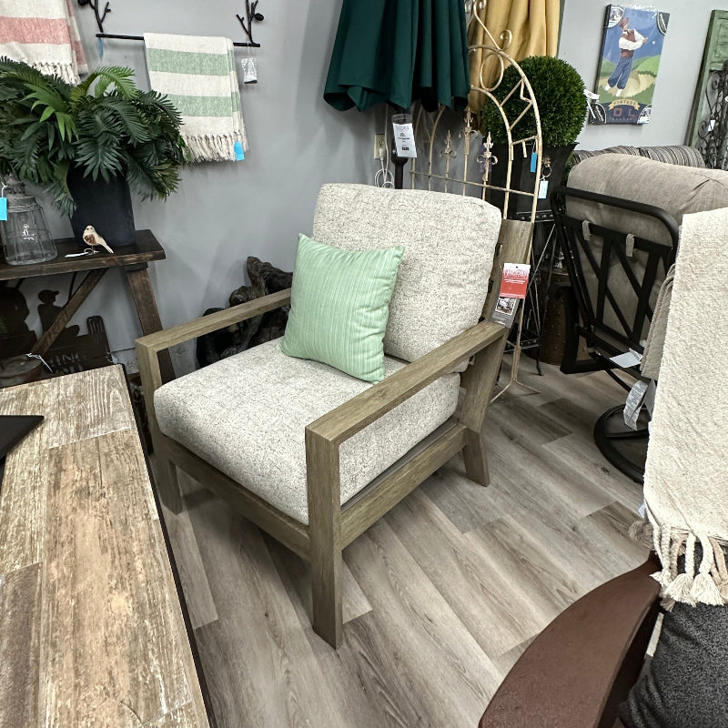 Outdoor furniture set with a wooden chair and cushioned bench against a wall with umbrellas and plants.