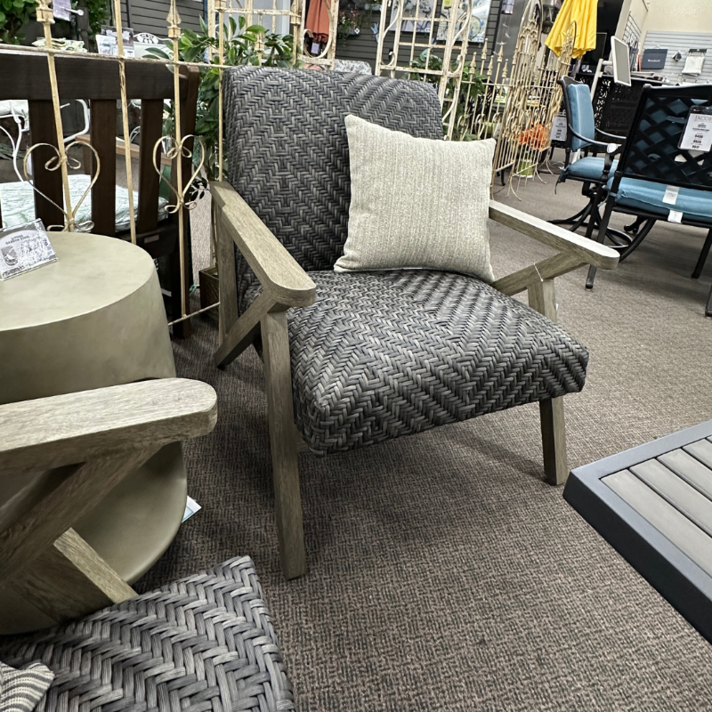Gray patterned armchair with a pillow in an indoor setting with furniture and decor.