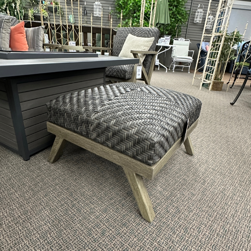Outdoor furniture set with a cushioned ottoman on a carpeted floor.