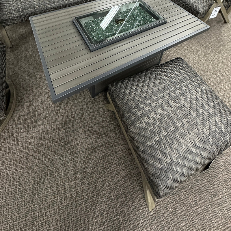 Outdoor patio furniture set with a fire pit table in a store setting.