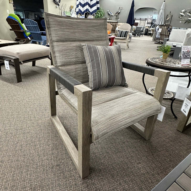 Outdoor furniture set including a chair with a striped pillow in a showroom setting.