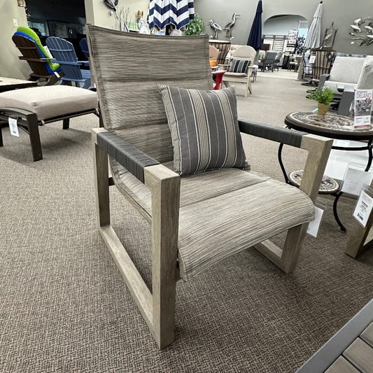 Outdoor furniture set including a chair with a striped pillow in a showroom setting.