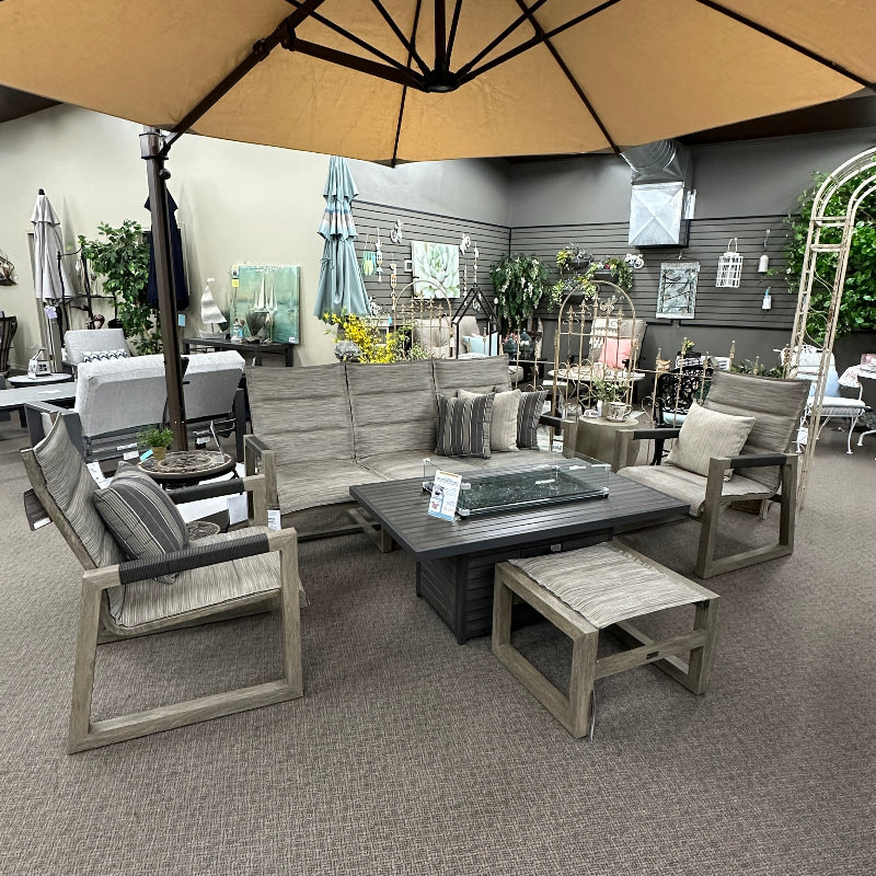 Outdoor patio furniture set with a large umbrella in an indoor showroom.