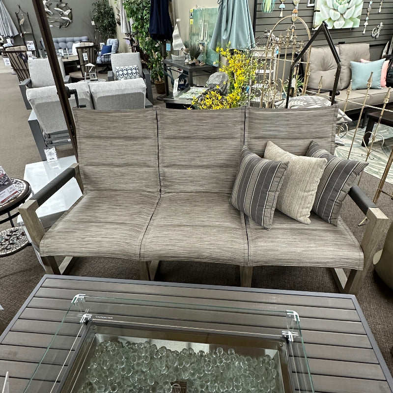 Outdoor patio furniture set with a fire pit table in a showroom setting.