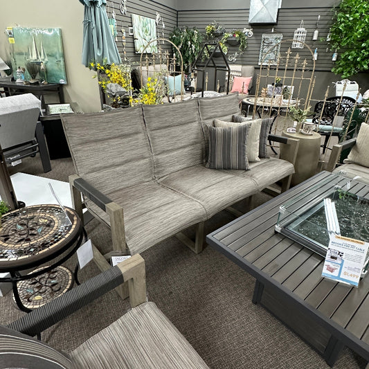 Outdoor furniture set with a sofa, chairs, and tables in a showroom setting.