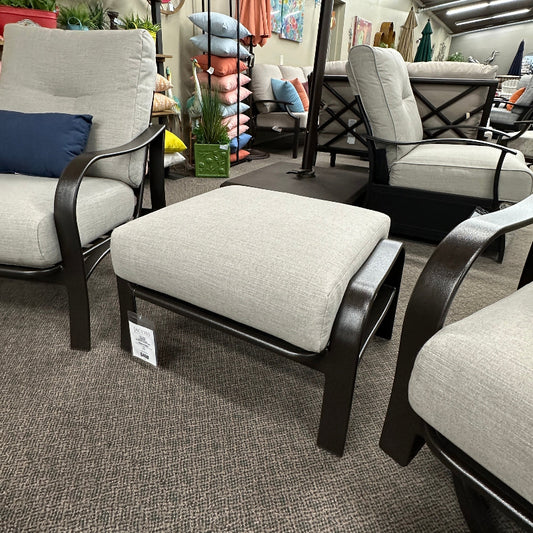 Outdoor furniture set with chairs and ottoman in a showroom setting.