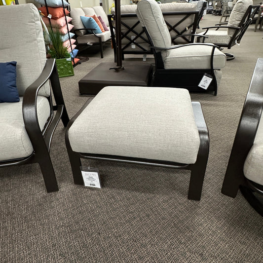 Outdoor furniture set with chairs and ottoman on a showroom floor.