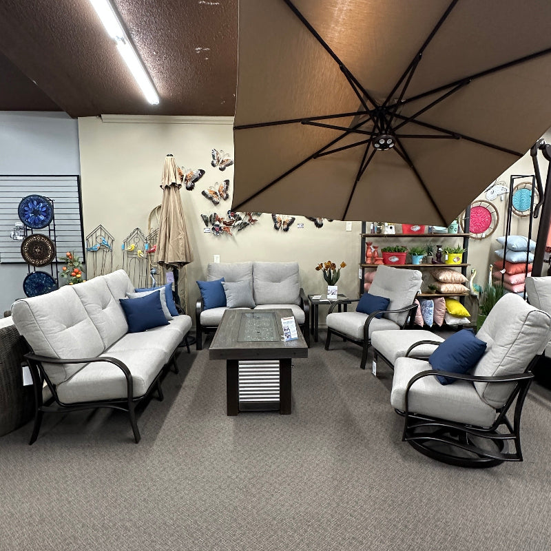 Outdoor furniture set with chairs, table, and umbrella in a showroom setting.