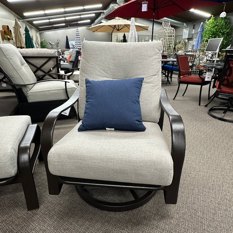 Outdoor furniture set with a chair featuring a blue pillow in a showroom setting.