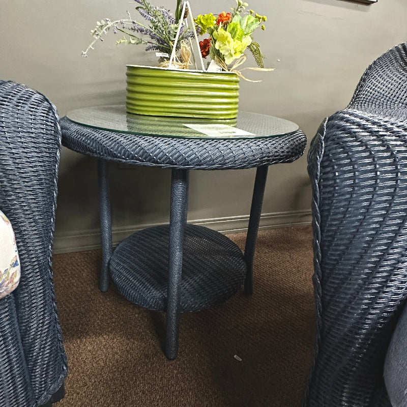 Small round table with decorative items between two wicker chairs in a room.