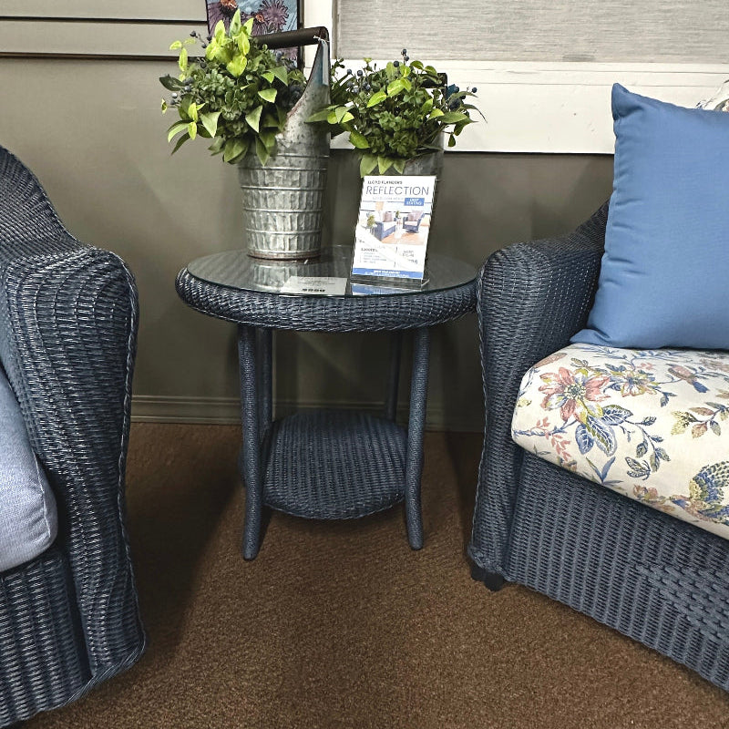 patio room with wicker chairs, a small table with plants, and a decorative pillow.