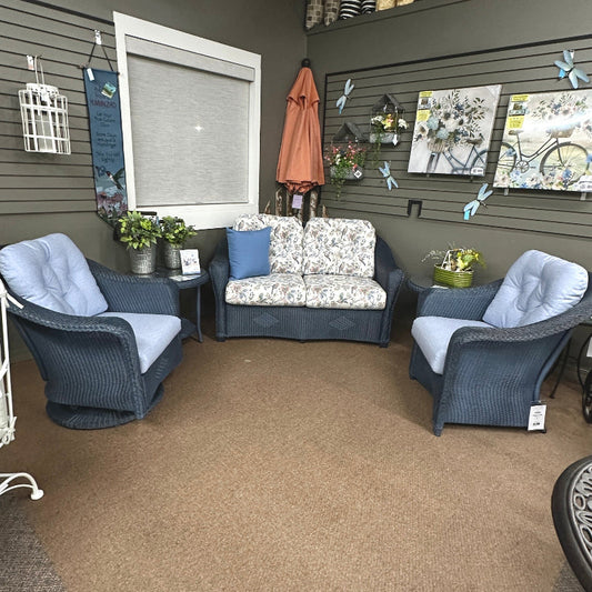 patio furniture showroom with gray chairs, floral-patterned sofa, and decorative items on shelves.