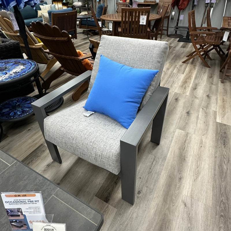 Gray chair with a blue pillow in a furniture store setting