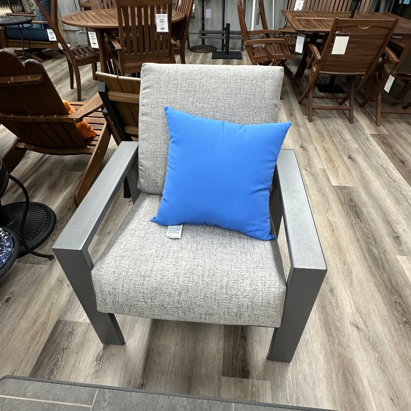 Gray chair with a blue pillow in a furniture store setting