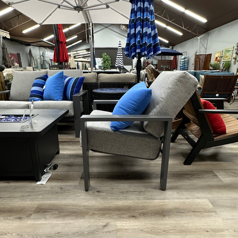 Modern living room with gray sofa, blue cushions, and a large umbrella in a showroom setting.