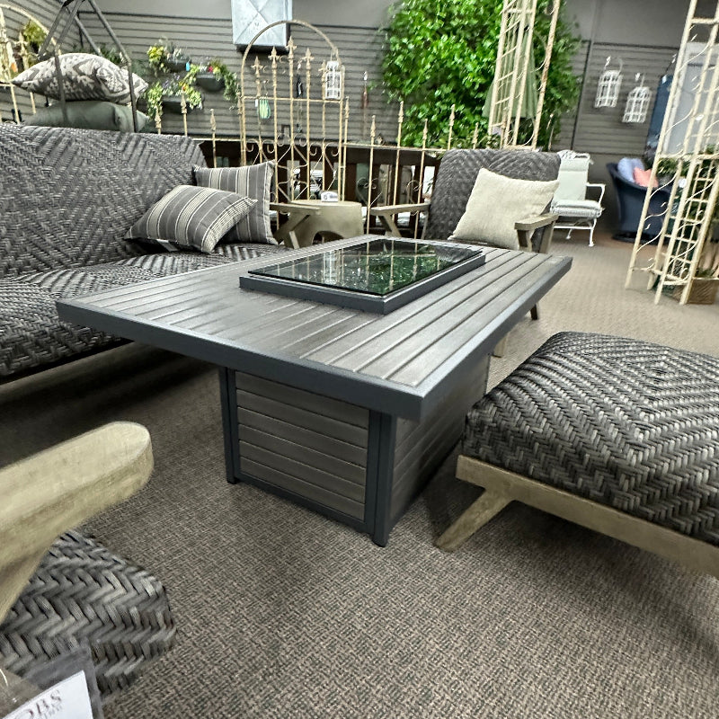 Outdoor furniture set with a fire pit table in an indoor showroom.