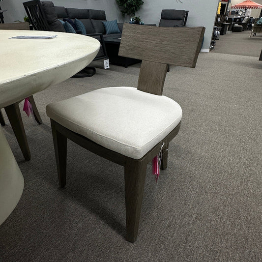 Chair with white cushion on a gray carpeted floor in an indoor setting