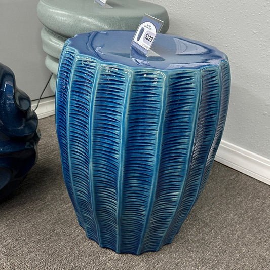 Blue textured side table on a gray carpeted floor with a neutral wall background