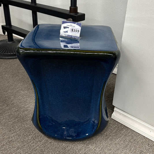 Blue stool with a price tag on a gray floor