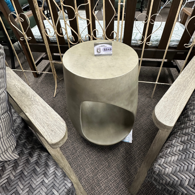 Round concrete side table with a textured surface in an outdoor setting.