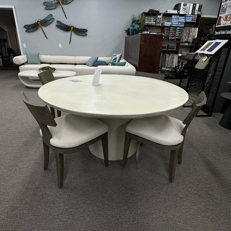 Round white table with chairs in a room with bookshelves and decorative elements.