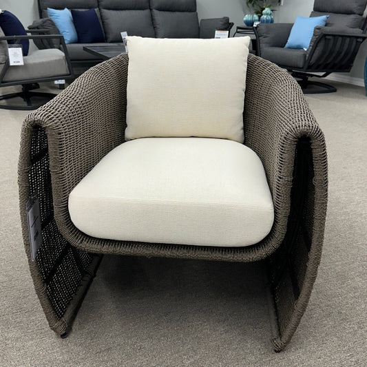 Wicker chair with white cushion in a room with gray walls and decorative elements.
