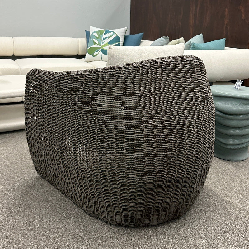 Wicker side table in a furniture store with sofas and decor in the background